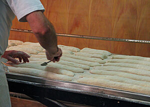 Mit gekonnten Schnitten werden die Baguettes vor dem Einschießen in den Ofen eingeschnitten. 