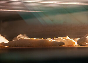 Mehrere Baguettes backen im Ofen hinter einer Glasscheibe.