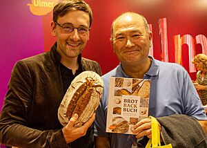 Lutz Geißler auf der Buchmesse in Frankfurt mit einem glücklichen Freikartengewinner mit seinem selbstgebacken Roggenmischbrot.