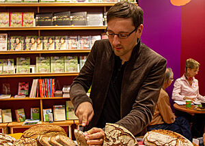 Lutz Geißler schneidet das Brot für die Brotverkostung an seinem Messestand auf der Buchmesse in Frankfurt.