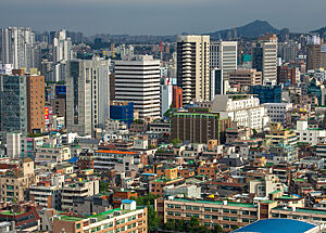 Blick über die riesige Stadt Seoul in Korea. Kleinere Häuser im Vordergrund, Wolkenkratzer im Hintergrund.