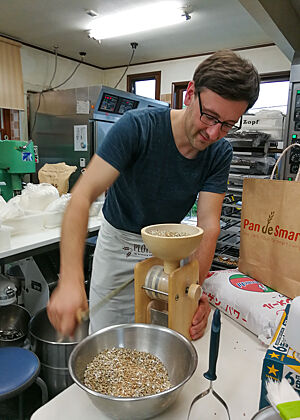Lutz Geißler zerkleinert Roggenkörner mit einer handbetriebenen Getreidemühle zu Schrot.