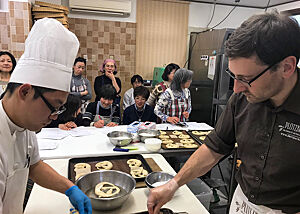 Lutz Geißler und ein japanischer Bäcker bearbeiten Laugenbrezeln.