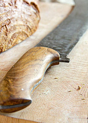Das Damast-Brotmesser hat einen edlen, ergonomisch geformten Holzgriff.