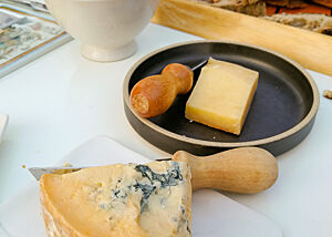 Auf einem Tisch liegen mehrere Sorten Käse und Brot zur Verkostung.