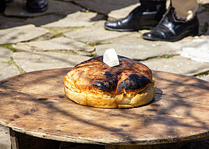Ein Brot und ein Stück Käse liegen auf einem runden Tisch.
