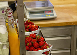 Auf dem Regal einer Backstube stehen Erdbeeren, Eier und weitere Zutaten.