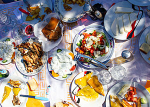 Auf einem gedeckten Tisch stehen u.a. Salat, Brot, Lammfleisch, Käse und eingelegte Paprika.