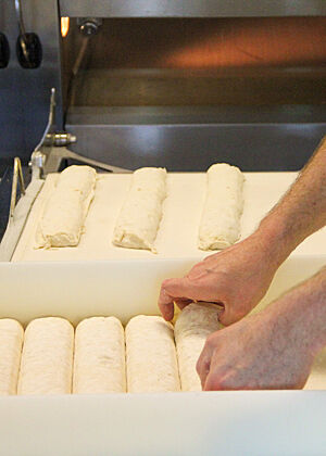 Die abgestochenen Teiglinge werden manuell aus der Teigwanne genommen und schonend auf den Abziehapparat des Ofens gesetzt.