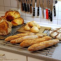 Auf mehreren Gitterrosten liegen Osterpinzen, Knauzenwecken, Baguettes und verschiedene Brote. 