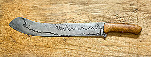Ein Damast-Brotmesser mit langer Klinge liegt auf einem Holztisch.