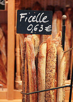 Eine kleine elsässische Bäckerei. Ein Ständer gefüllt mit Ficelle (sehr dünne Baguettes), natur oder mit verschiedenen Körnern bestreut.