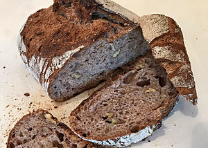Nussbrot im Anschnitt. Im Anschnitt des rustikalen Nussbrotes werden Walnussstücke in der lockeren Krume sichtbar.