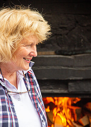 Roswitha Huber auf der Kalchkendlalm vor dem Holzbackofen der gerade angefeuert wurde.