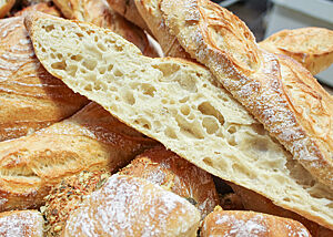Die Präsidentenbaguettes mit herrlicher Porung. Ein längs aufgeschnittenes Präsidentenbaguette mit grobporiger Krume liegt auf weiteren Gebäckstücken der Backnacht.