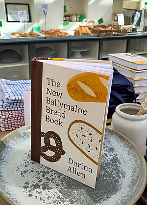 Das aktuellste Brotbackbuch von Darina Allen im Shop ihrer Kochschule. Das Buch "The New Ballymaloe Bread Book" steht auf einem Teller.