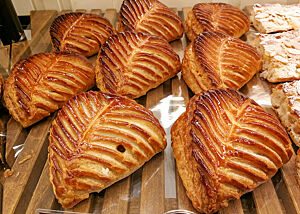 Kunstvoll als Blätter gestaltete gefüllte Blätterteigtaschen liegen in der Auslage einer Bäckerei.