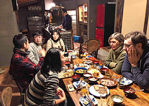 Geselliges Abendessen unter Freunden. Lutz Geißler sitzt mit japanischen Freunden am gedeckten Tisch.