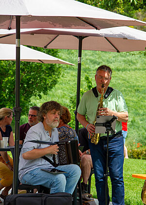Zwei Männer spielen Jazz unter einem Sonnenschirm.