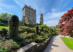 Die Parkwelt um Blarney Castle. Grün- und Rottöne am Wegesrand, im Hintergrund ein Teil von Blarney Castle.