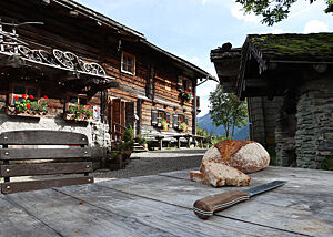 Auf einem rustikalen Holztisch liegt ein kräftig ausgebackenes Brot mit Mehl auf der Kruste.