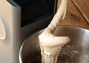 Ein weicher Mischteig aus Roggen, Weizen und Dinkel; mit dem Spiralhaken geknetet. Der helle Teig aus Roggen, Weizen und Dinkel fällt schwerreißend von dem hochgestellten Knethaken.
