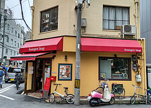 Die Fassade der Bäckerei ist warmgelb gestrichen. Rote Markisen ziehen die Blicke auf den Laden.