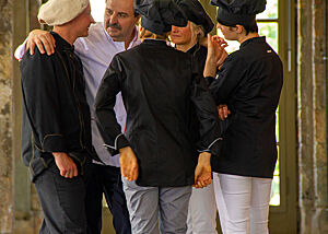 Johann Lafer ist im Gespräch mit einem vierköpfigen Bäckerteam in schwarz-weißer Arbeitskleidung.
