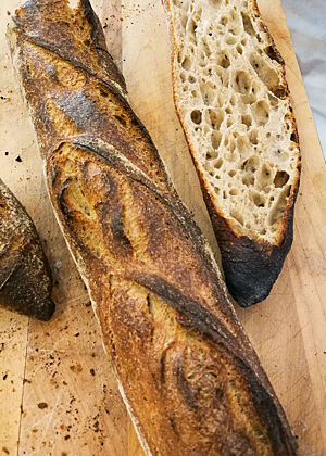 Blaires Baguette – das beste Baguette, das ich je gegessen habe. Ein dunkel ausgebackenes Baguette zeigt im Anschnitt seine grobporige Krume.