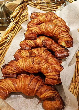 Nach Art des Hauses geformte Croissants. Lange Croissants mit breiten Enden liegen in der Auslage einer Bäckerei.