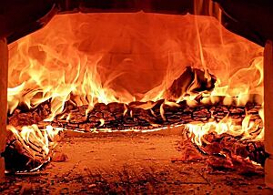 Der Holzbackofen der Kalchkendlalm wird angeheizt. Die Holzscheite im Inneren des Holzbackofens auf der Kalchkendlalm brennen mit goldener Flamme lichterloh.