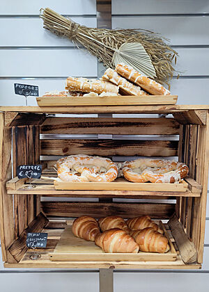 Brezeln und nicht tourierte „Croissants“ in My Patrik's Bakery. Eine an der Wand montierte Holzkiste mit Backwaren.