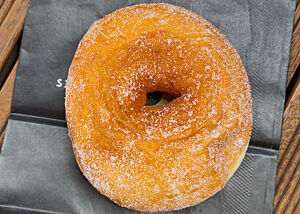 Ein Bagel „ohne alles“ von der Bäckerei The Rolling Donut in Dublin. Ein goldbrauner, bezuckerter Bagel liegt auf einer schwarzen Papiertüte.