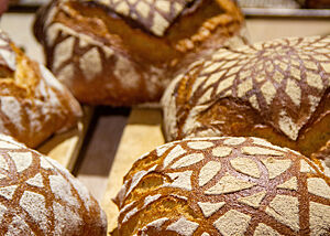 Mehrere Brote sind mit kunstvollen Mehlmustern auf der Oberfläche verziert.