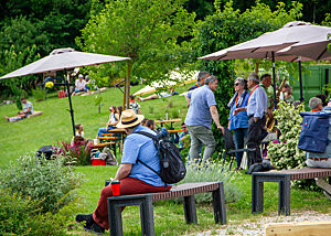 Blick auf die Wiese vor der Bäckerei mit vielen einzelnen und in Gruppen zusammenstehenden Teilnehmern des Brotfestes.