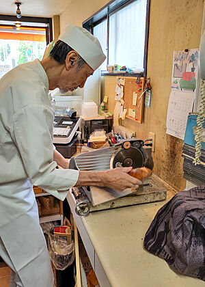 Yuji Koyama schneidet Baguette an seiner Brotschneidemaschine. 