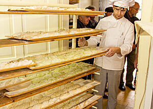 Anschließend geht es zum Altdeutschen Ofen. Bäckermeister Fischer schiebt einen Wagen mit Zwirbelbaguette-Teiglingen zum Altdeutschen Ofen.