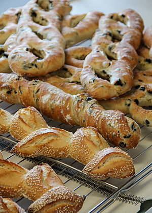 Wurzelbrot, Pain d’Épi, Fougasse. Fertig ausgebacken kühlen die goldbraun gebackenen Wurzelbrote mit Oliven, Pain d’Épi und Fougasse mit Oliven aus.