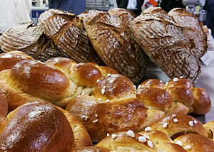 Butterzöpfe und mehr für rund 60 Profis und Hobbybäcker. Goldbraun ausgebackene Butterzöpfe liegen vor rustikal ausgebackenen Brotlaiben.