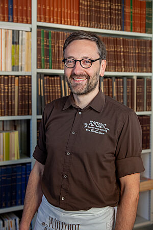 Lutz Geißler steht vor einem Bücherregal seiner Brotbuch-Bibliothek.