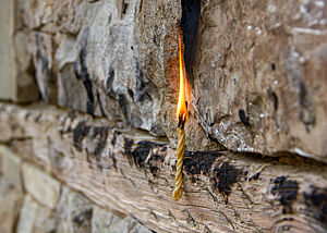 Die sehr dünne brennende Bienenwachskerze wurde an eine Kirchenmauer gepresst.