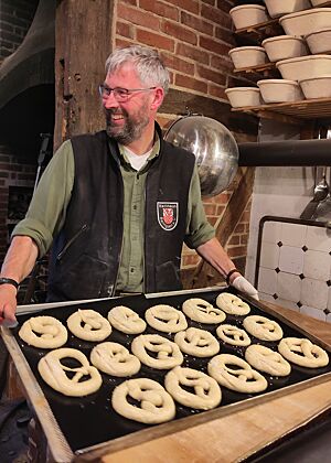 Ab in den Ofen Harald trägt ein Blech mit fertigen Brezeln zum Ofen, um sie abzubacken.