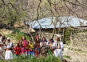 Ein Teil der albanischen Folkloregruppe mit farbenfrohen Trachten steht vor einer Hütte.