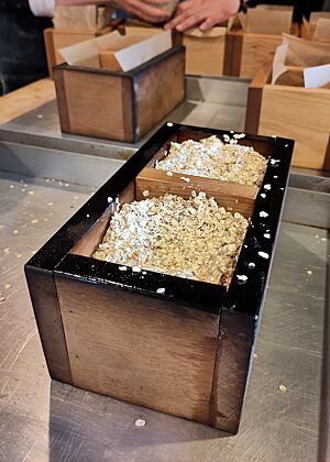Mit Haferflocken bestreute Teiglinge sitzen in einem bereits eingebrannten Holzrahmen. Die Teiglinge, hier in einem eingebrannten Holzrahmen, werden glattgestrichen und mit Haferflocken bestreut.