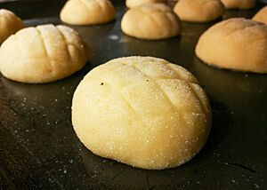Melonenbrötchen von Zopf vor dem Backen. Die noch nicht gebackenen Melonenbrötchen-Teiglinge haben eine gezuckerter Oberseite mit leichtem Rautenmuster.