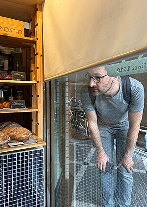 Drinnen kein Platz mehr! Lutz Geißler steht vor dem Ladenschaufenster und schaut in den Laden hinein.