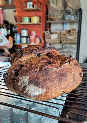 Ein reines Sauerteigbrot mit Rosinen in der Bäckerei Nourish in Dingle. Ein dunkel gebackenes Brot liegt auf einem Gitterrost auf der Theke.
