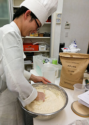 Poolish. Ein japanischer Bäcker knetet mit seinen Händen einen Vorteig in einer Schüssel.