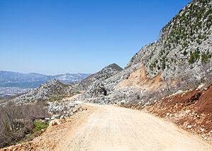 Die schmale Straße in den Bergen von Albanien besteht aus festgefahrenem Schotter und Erde.