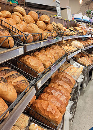 Die Auslage der Bäckerei Bácús in Dingle. Viele goldbraune Weißbrote und Brötchen auf mehreren Ebenen in einem Regal.